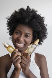 vue de face smiley femme tenant des produits capillaires